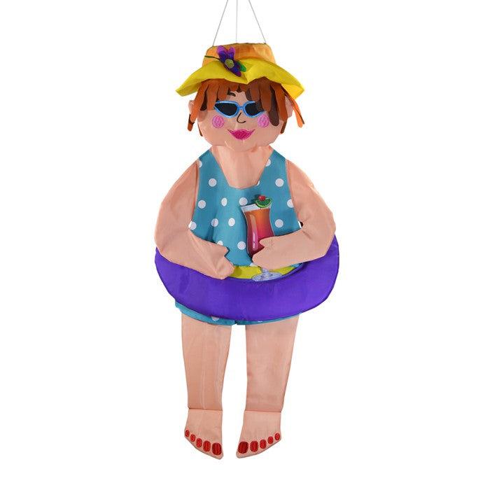The 3D Beach Bev windsock has detailed appliquéd design and embroidered accents. Measuring 31”, this windsock features a lady in a swimsuit and hat, holding a tropical drink, and wearing an inner tube around her belly.