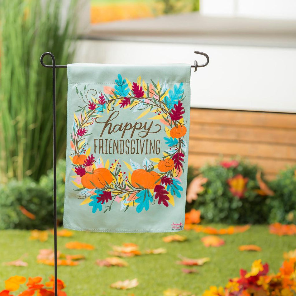 The Happy Friendsgiving garden flag features a wreath of fall leaves and pumpkins around the words "Happy Friendsgiving".
