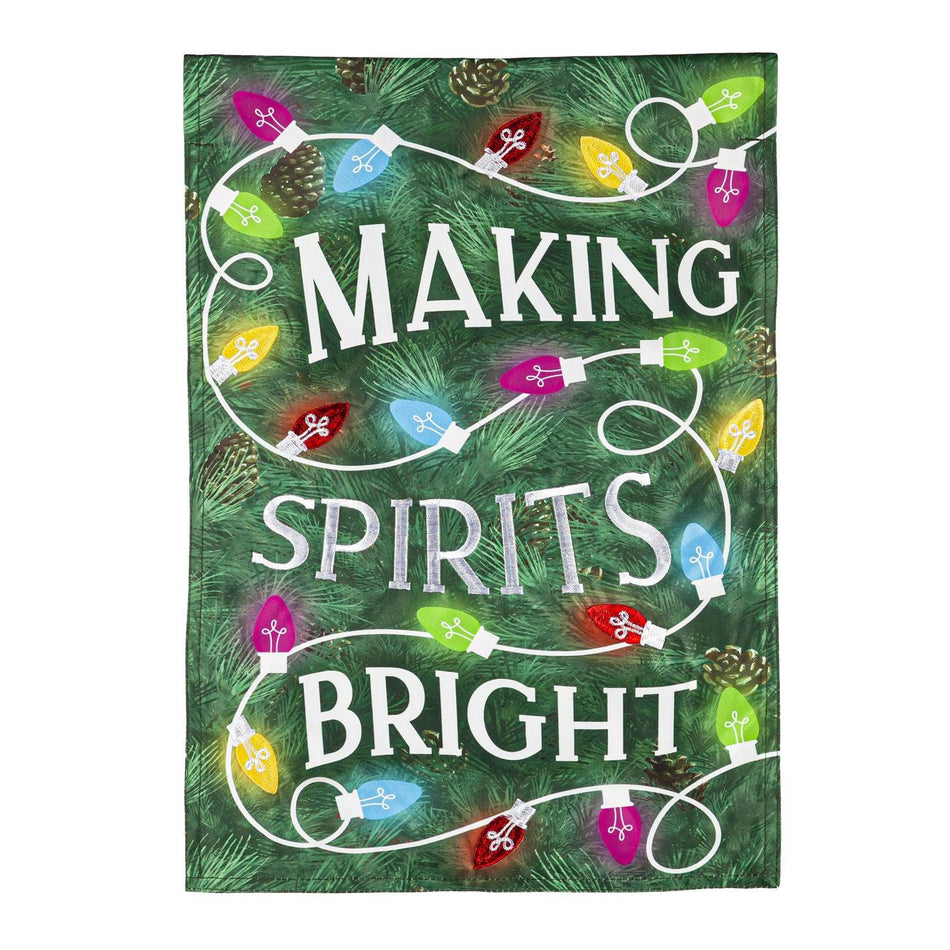 The Making Spirits Bright garden flag features a green pine needle background with a string of brightly colored Christmas lights.