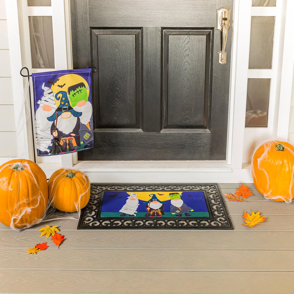 The Trick or Treat Gnomes garden flag features a trio of gnomes dressed in Halloween costumes and ready for trick or treating.