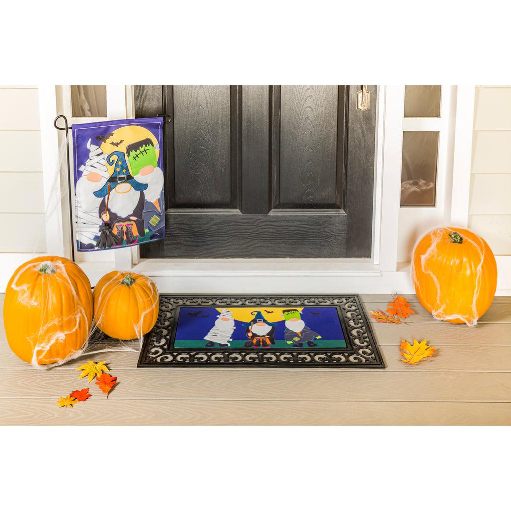 The Trick or Treat Gnomes garden flag features a trio of gnomes dressed in Halloween costumes and ready for trick or treating.