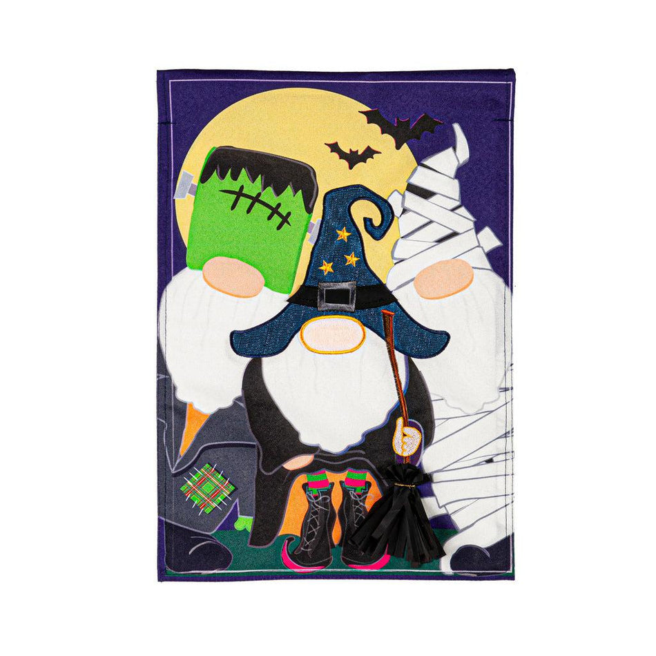 The Trick or Treat Gnomes garden flag features a trio of gnomes dressed in Halloween costumes and ready for trick or treating.