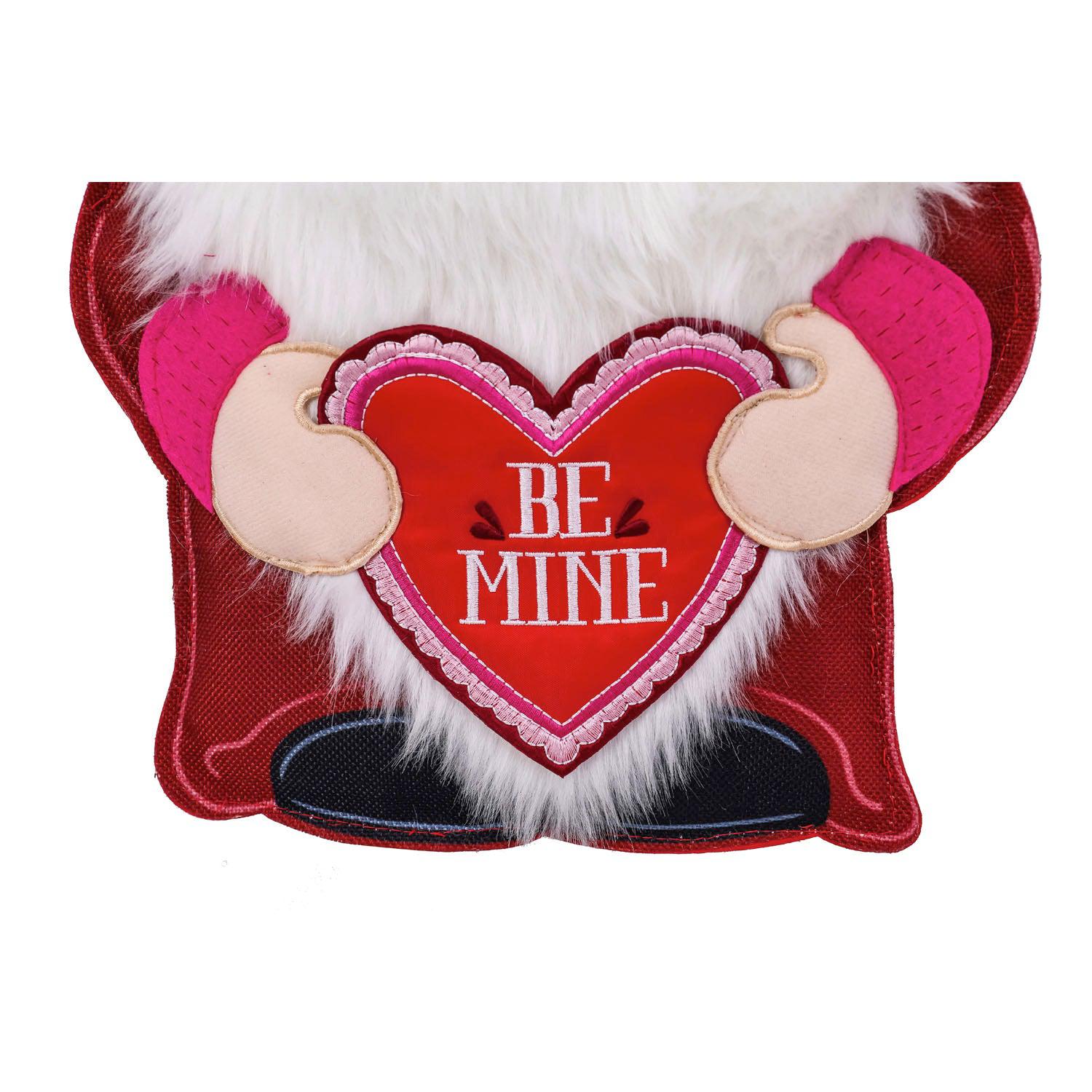 The Valentine Gnome Door Décor features a gnome dressed in red holding a heart with the words "Be Mine". 