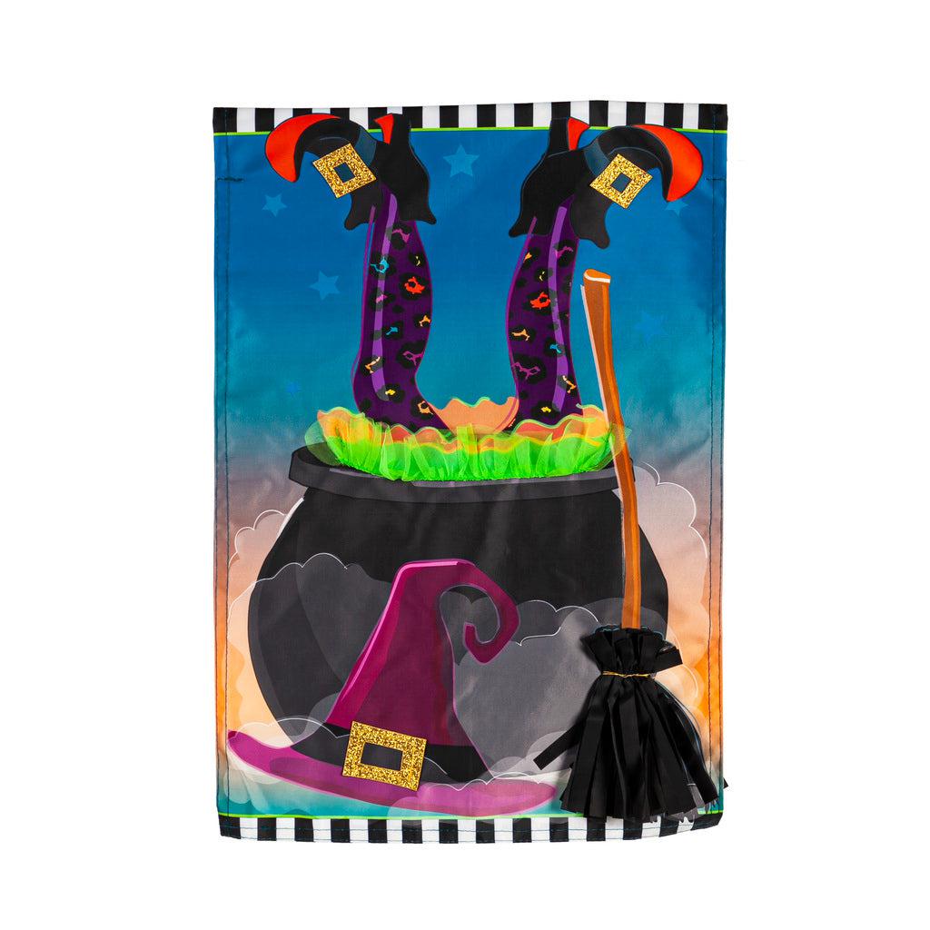 The Witches Cauldron garden flag features a witches legs sticking out of a cauldron and her hat and broom leaning against the cauldron.