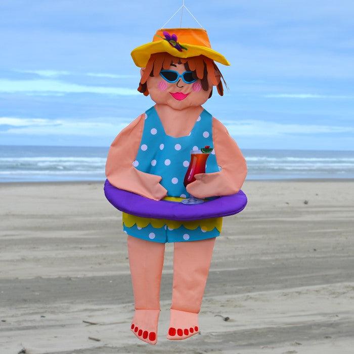 The 3D Beach Bev windsock has detailed appliquéd design and embroidered accents. Measuring 31”, this windsock features a lady in a swimsuit and hat, holding a tropical drink, and wearing an inner tube around her belly.