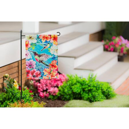 The Bright Flowers and Hummingbirds garden flag features a pair of hummingbirds flying among a multitude of brightly colored flowers. 