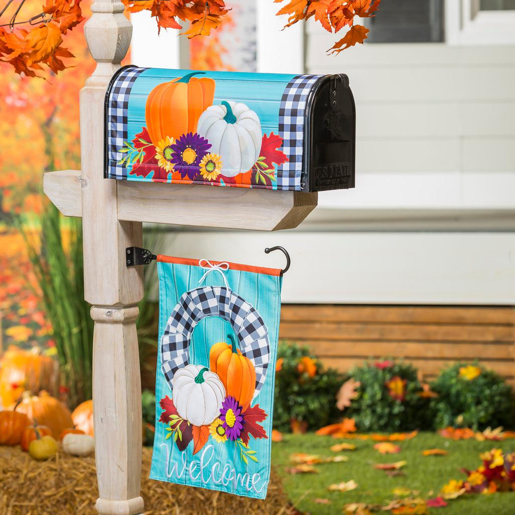 Our Buffalo Check Fall Wreath garden flag features a black and white checked wreath decorated with pumpkin and flowers and the word "Welcome". 