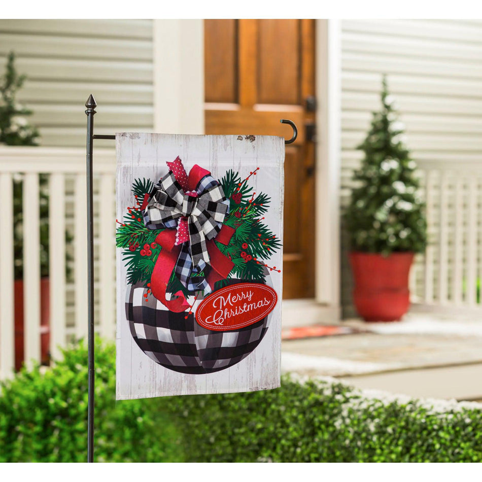 The Buffalo Check Ornament garden flag features a checked ornament with bows and pine along with the words "Merry Christmas". 