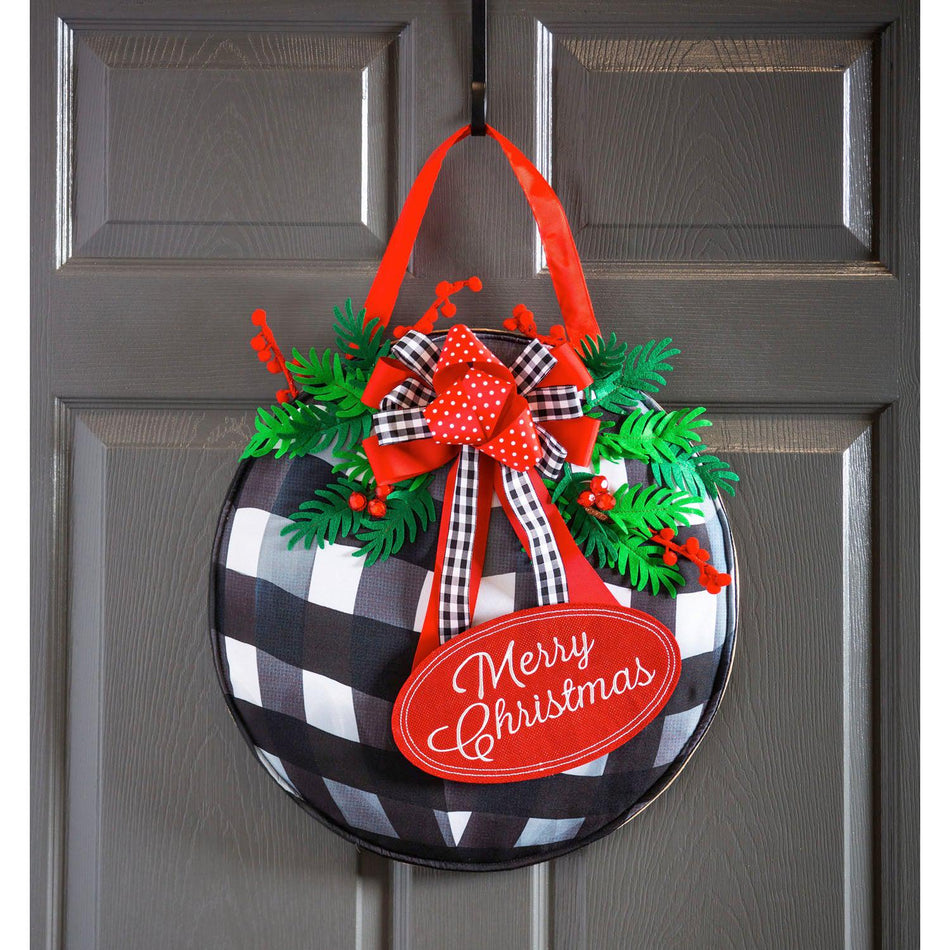 Let the beautiful Buffalo Check Ornament Door Décor greet your visitors this holiday season! It features a checked ornament with bows and pine along with the words "Merry Christmas", and is made from poly-burlap fabric for outdoor use.