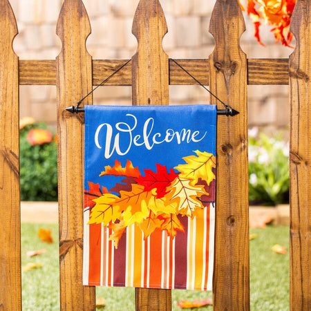 The Cascading Leaves garden flag features bright fall leaves with coordinating stripes and the word "Welcome" across a vivid blue top. 