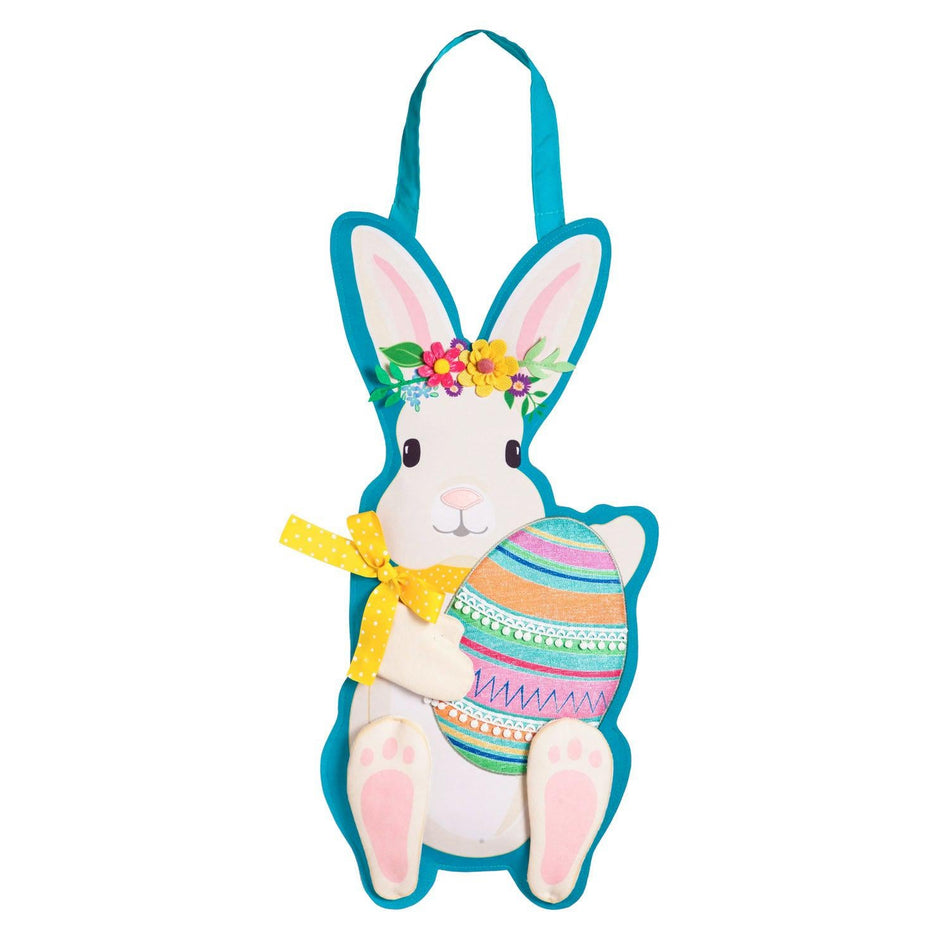 The Easter Bunny Door Décor features a white bunny with a floral crown and yellow ribbon holding an Easter egg. 