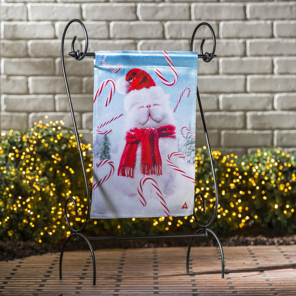 The Fluffy Cat Snowman garden flag features a fluffy white cat, wearing a red scarf and Santa hat, with candy canes floating around him.