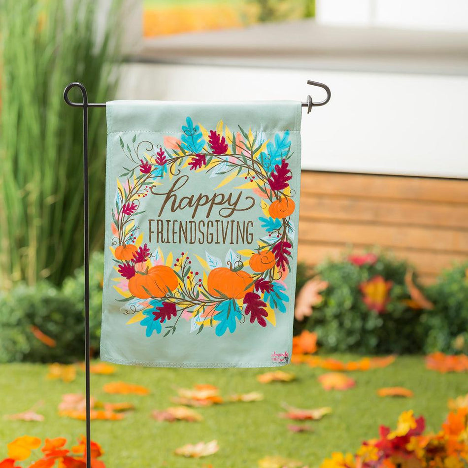 The Happy Friendsgiving garden flag features a wreath of fall leaves and pumpkins around the words "Happy Friendsgiving". 