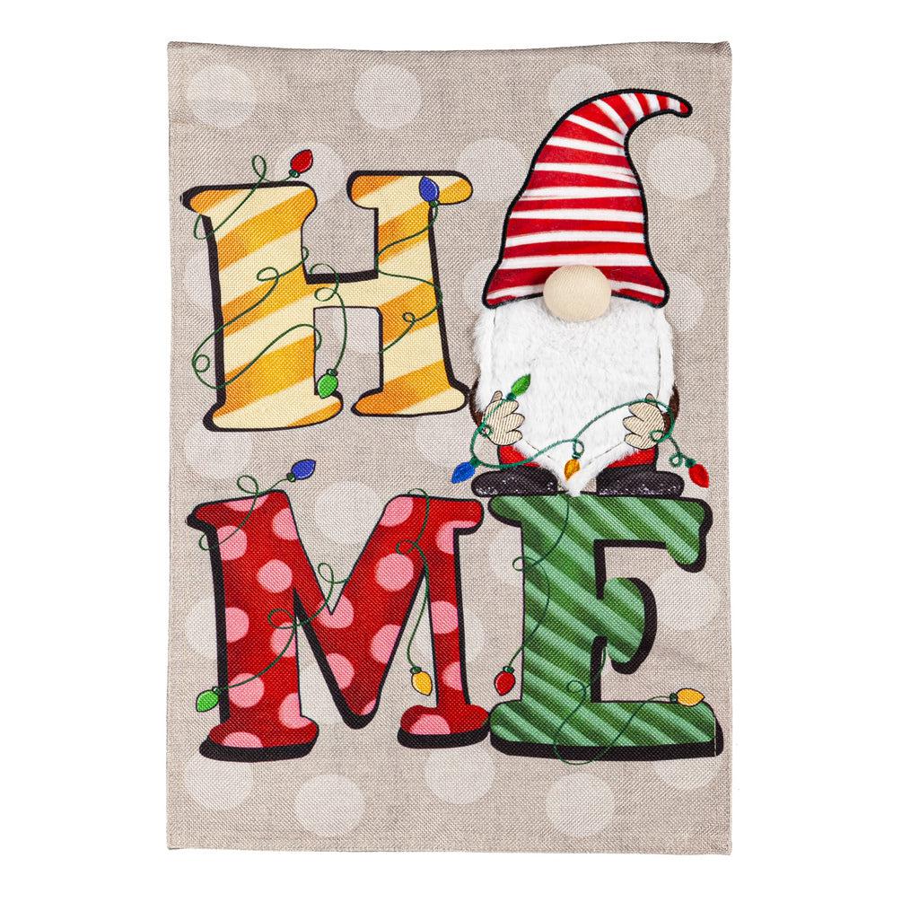 The Home Gnome garden flag features the word "HOME" in holiday colors with a gnome replacing the "O" and holding a string of lights. 