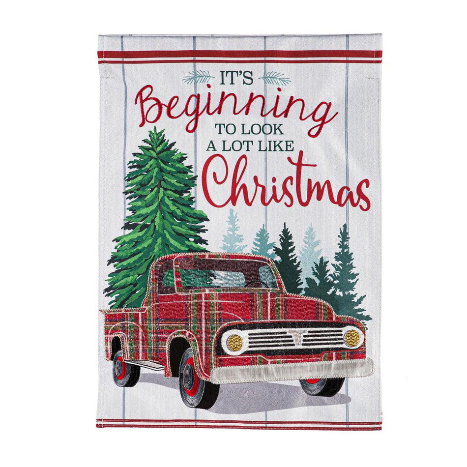 The Plaid Christmas Truck garden flag features a vintage plaid truck, pine trees, and the words "It's Beginning to Look a Lot Like Christmas". 