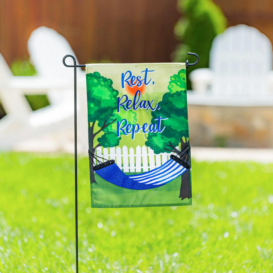 The Rest, Relax, Repeat Hammock garden flag features a blue and white striped hammock strung between two trees and the words "Rest, Relax, Repeat". 