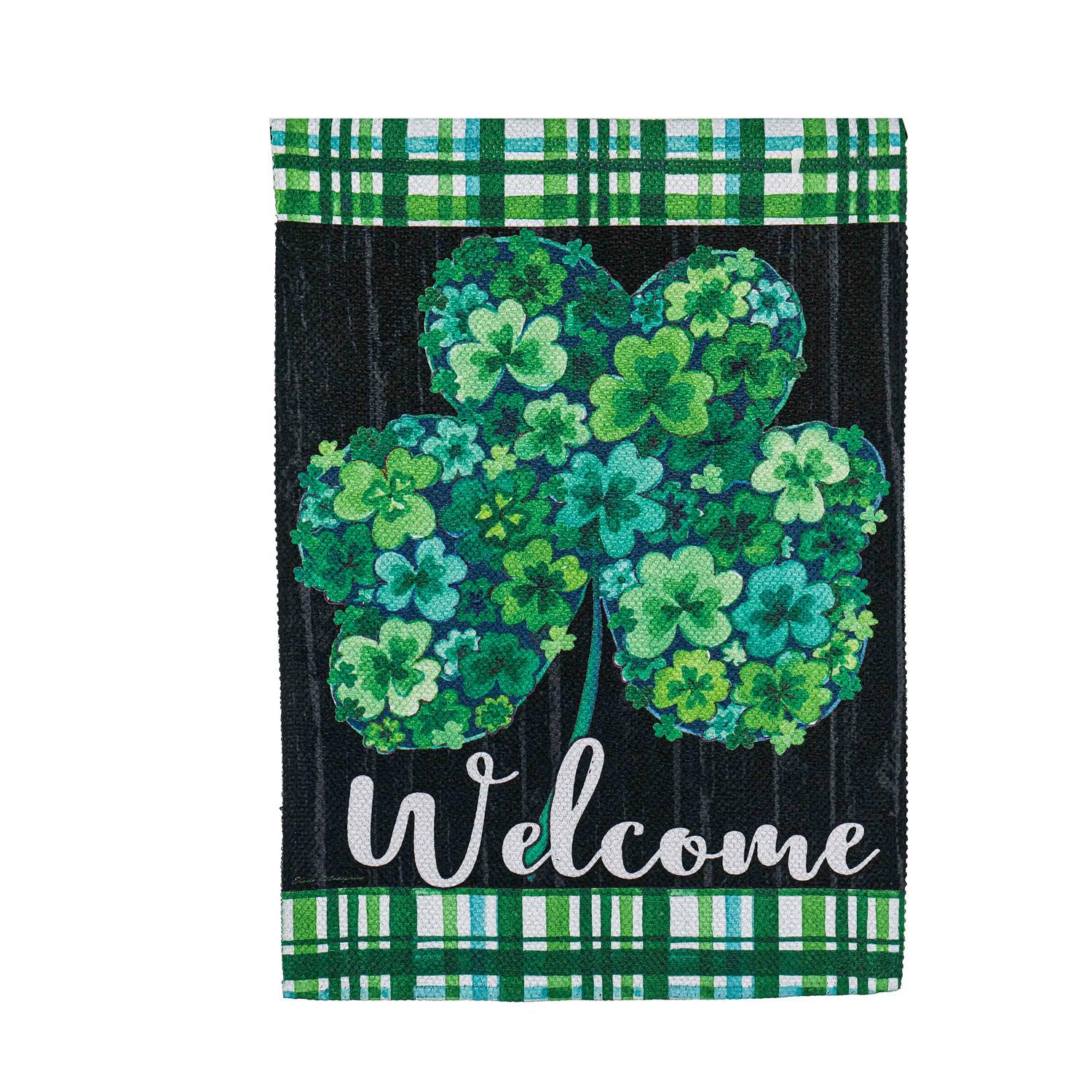 The Shamrock Flowers garden flag features a shamrock with a floral motif, plaid accents, and the word "Welcome". 