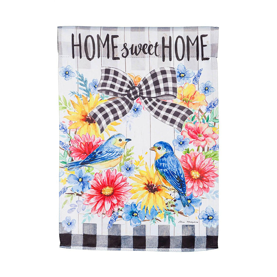 The Spring Bird Wreath garden flag features a spring floral wreath with a pair of bluebirds, black checked accents, and the words "Home Sweet Home".