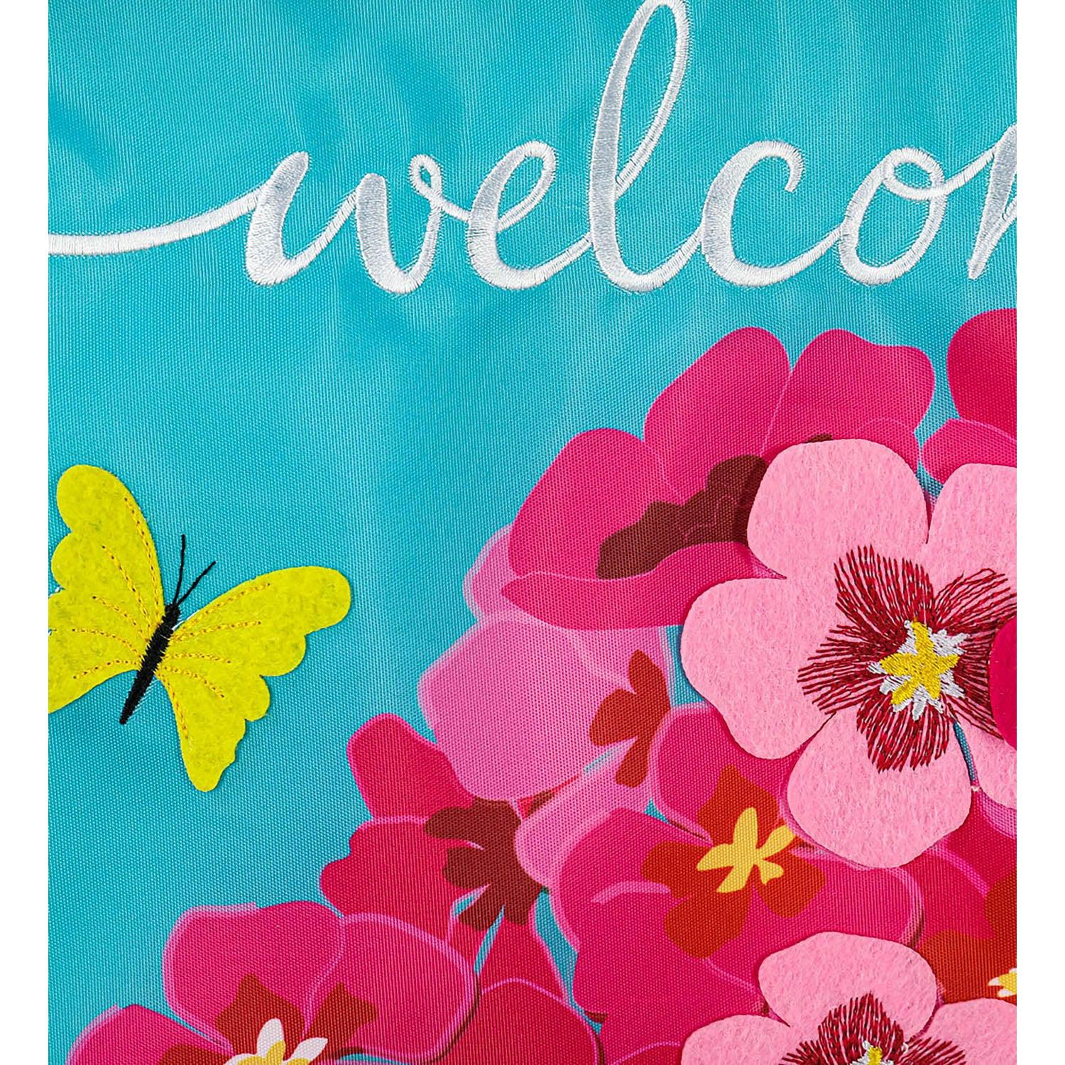 The Spring Geraniums garden flag features vivid pink geraniums with hot pink checked top and bottom borders and the word "Welcome" across the top.