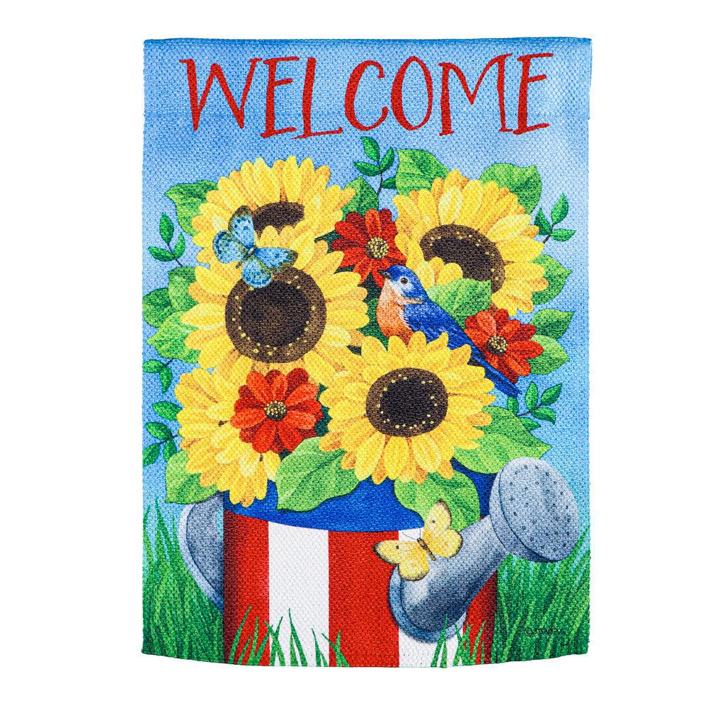 The Stars and Stripes Watering Can house banner features bright yellow flowers in a patriotic watering can and the word "Welcome" across the top. 