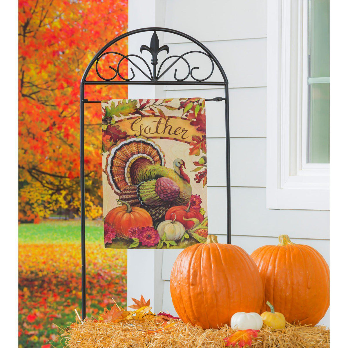 The Warm Gathering Turkey garden flag features a turkey resting among pumpkins and the word "Gather" surrounded by fall leaves. 