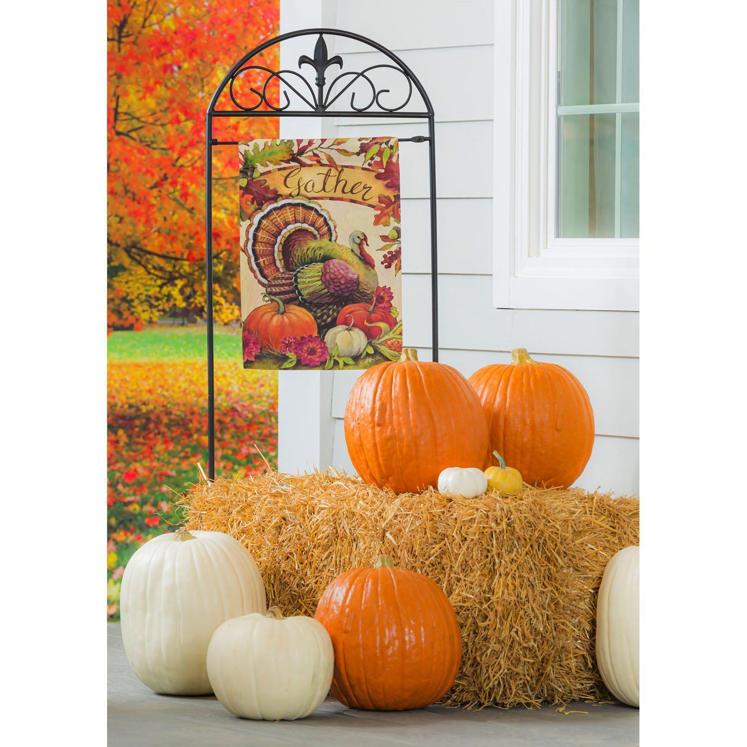 The Warm Gathering Turkey garden flag features a turkey resting among pumpkins and the word "Gather" surrounded by fall leaves. 