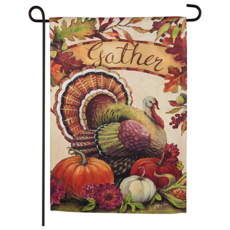 The Warm Gathering Turkey garden flag features a turkey resting among pumpkins and the word "Gather" surrounded by fall leaves. 