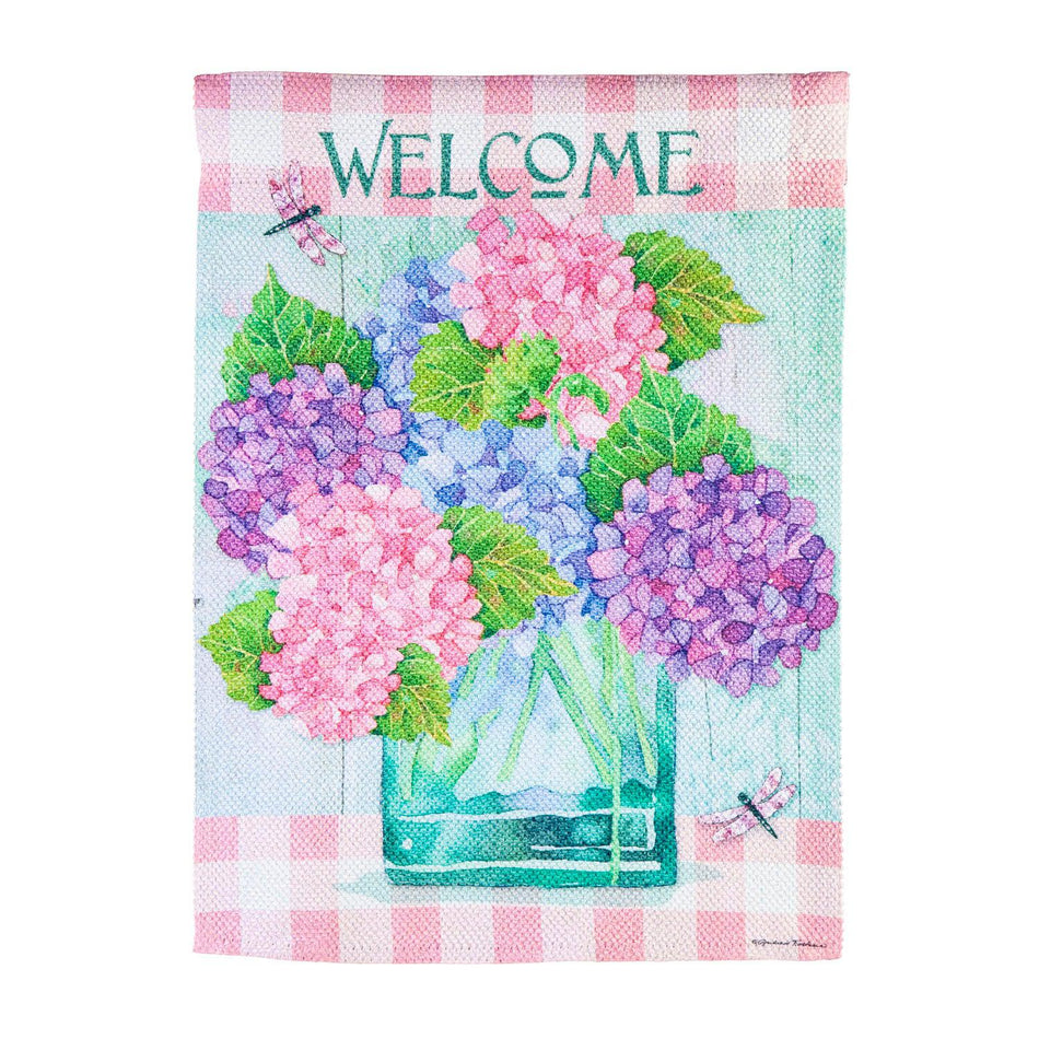 The Welcome Hydrangeas garden flag features pink, blue, and lavender hydrangeas in a vase, a pink checked top and bottom border, and the word "Welcome "across the top. 