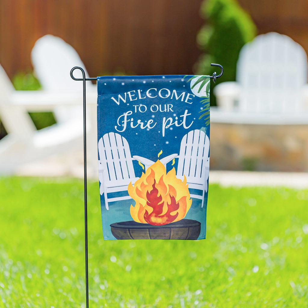The Welcome to Our Firepit garden flag features lawn chairs, a roaring fire, and the words "Welcome to Our Firepit" across the top. 