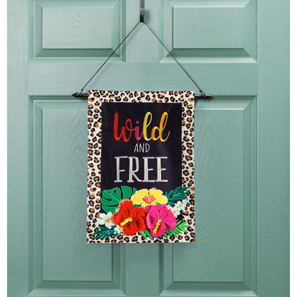 The Wild and Free garden flag features bright flowers, a black background, a border of leopard spots, and the words "Wild and Free".