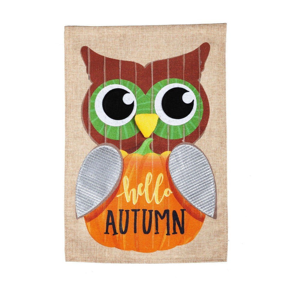 The Wood Plank Owl garden flag features a wide-eyed owl holding a pumpkin with the words "Hello Autumn". 